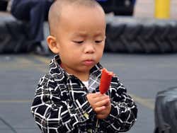 Menino comendo uma salsicha